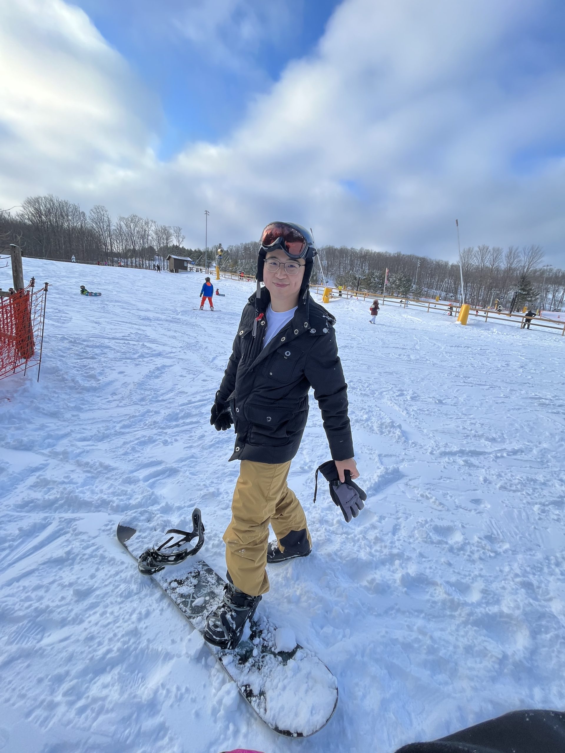 Kaison standing with his snowboard at the base area